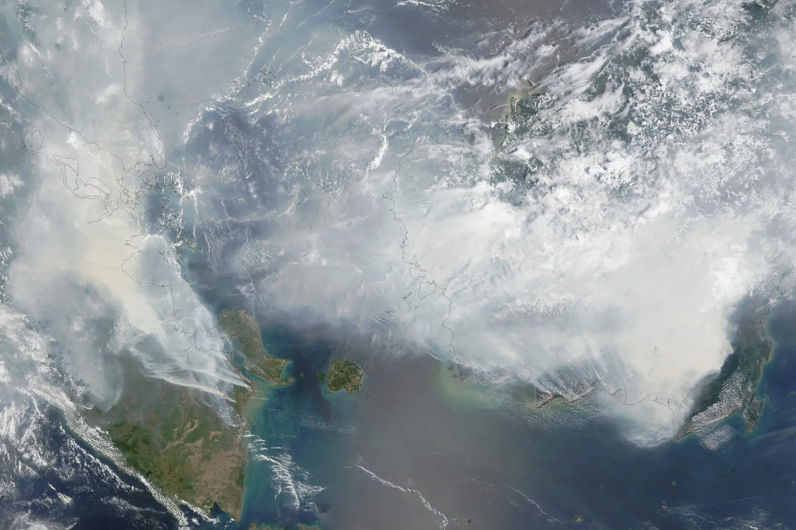 Satellite image of Sumatra and Borneo hidden under grey smoke with red fire markers.